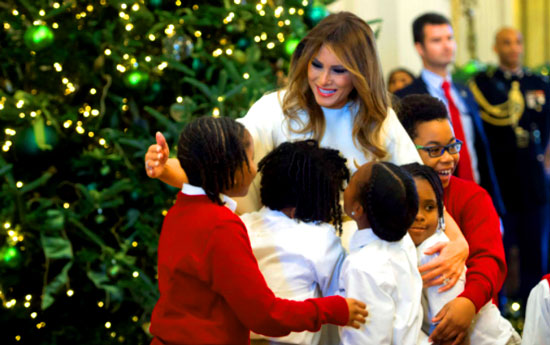 US First Lady Melania Trump hugs children in the East Room as she tours Christmas decorations at the White House in Washington, DC, November 27, 2017. / AFP PHOTO / SAUL LOEB - Breitbart